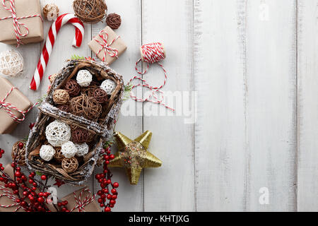 Boules de Noël en rotin panier, jouets, décorations, d'or et présente les coffrets cadeaux enveloppés dans du papier kraft blanc sur fond de bois, copy space Banque D'Images