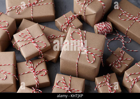 Cadeau de Noël ou boîtes présent enveloppé dans du papier kraft à rayures avec ficelle Baker's string sur fond de pierre texturés Banque D'Images