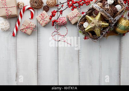 Boules de Noël en rotin panier, jouets, décorations, d'or et présente les coffrets cadeaux enveloppés dans du papier kraft blanc sur fond de bois, copy space Banque D'Images