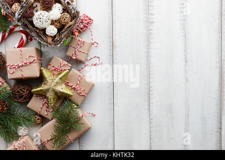 Les jouets de Noël, décorations, cadeaux et coffrets cadeaux enveloppés dans du papier kraft blanc sur fond de bois, copy space Banque D'Images