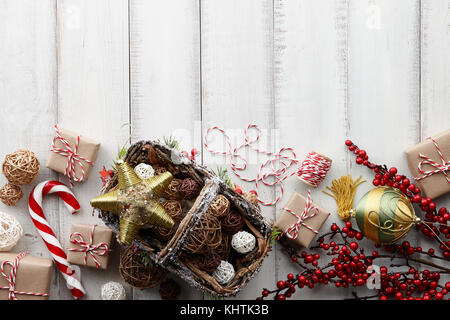 Boules de Noël en rotin panier, jouets, décorations, d'or et présente les coffrets cadeaux enveloppés dans du papier kraft blanc sur fond de bois, copy space Banque D'Images