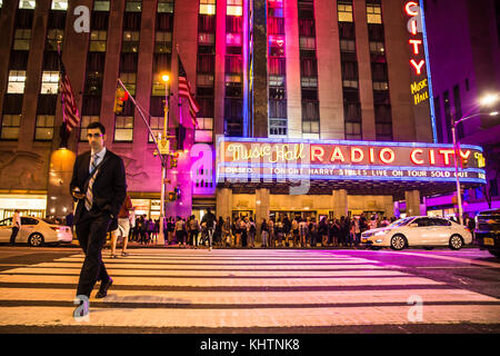 New York - 28 septembre 2017 : Vue de nuit occupée scène de rue à l'extérieur de Radio City Music Hall, le sixième avenue à Manhattan. Banque D'Images