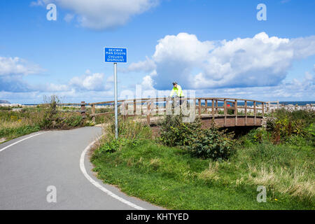 Les cyclistes démonent le panneau, avant le pont, sur Wales Coast Path UK Banque D'Images