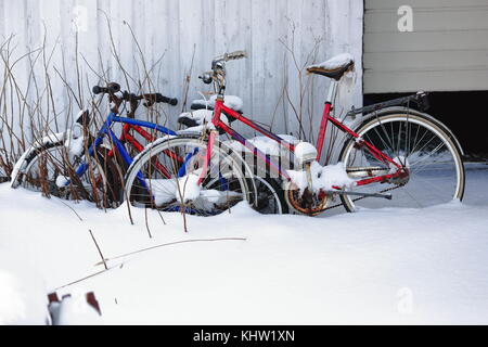 Vieux-rusty-abandonnés a laissé de côté des bicyclettes sous une couverture de neige épaisse s'appuyant sur le mur d'une cabane de pêche en attente de l'été à venir et être réutilisés Banque D'Images