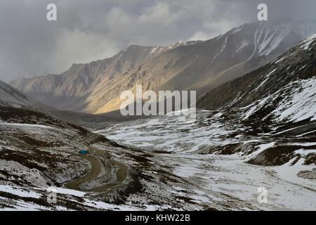 Vallée de montagne couverte de neige avec une route de campagne serpentine sur la gauche la pente. Banque D'Images