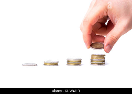 Homme met une pièce sur une pile de pièces sur fond blanc avec concept de revenu croissant Banque D'Images