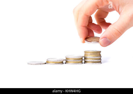 Homme met une pièce sur une pile de pièces sur fond blanc avec concept de revenu croissant Banque D'Images