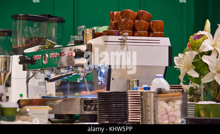 Une machine à café avec une pile de coupes sur le dessus. Banque D'Images