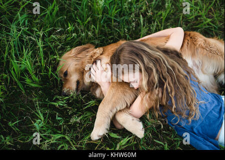 Vue de dessus de girl lying on grass hugging golden retriever dog Banque D'Images