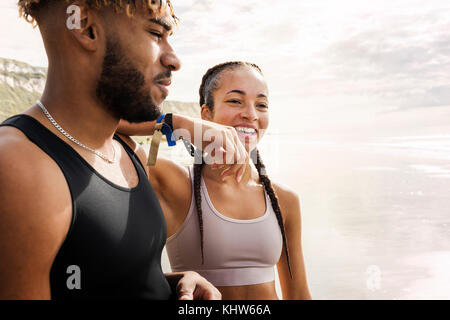 Jeune coureuse reposant sur le bras de l'épaule du jeune homme sur la plage Banque D'Images