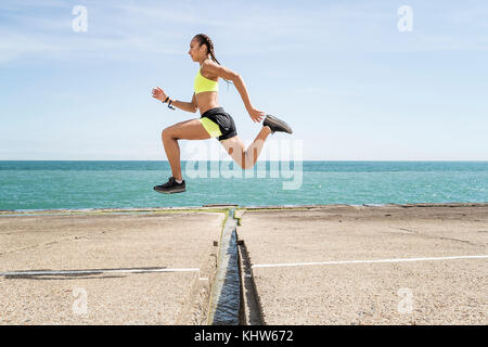 Jeune femme tournant à l'extérieur, saute au-dessus de gap en pont, mid air Banque D'Images