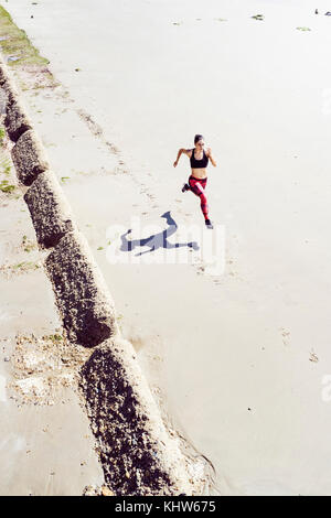 Young woman running along beach view Banque D'Images