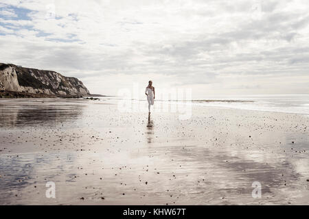 Young woman running along beach Banque D'Images