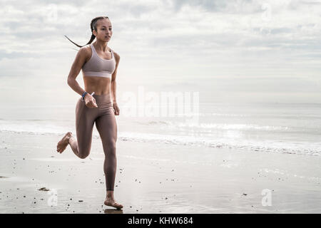 Young woman running along beach Banque D'Images