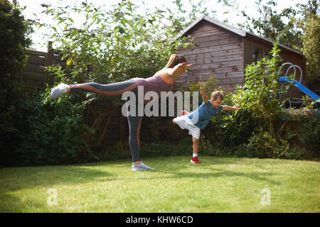 La mère et le fils dans l'exercice de jardin, debout dans la position de yoga Banque D'Images