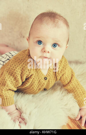 Portrait de blue eyed baby garçon couché sur un tapis en peau de mouton Banque D'Images