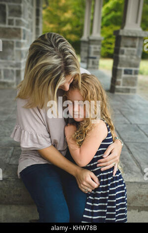 Mère fille consolant sur Front Porch Banque D'Images