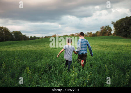 Frères marche sur terrain herbeux vert Banque D'Images