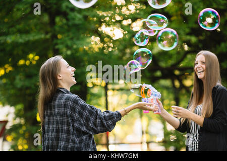 Deux jeunes amis féminins faisant des bulles flottantes dans park Banque D'Images