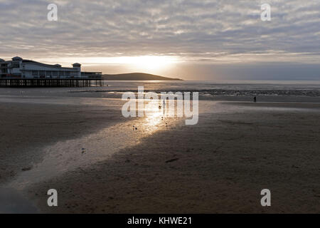 Weston-super-Mare, Royaume-Uni. 19 novembre, 2017. Météo France : chiens de promeneurs sur la plage sont silhouette sur le coucher de soleil à la fin d'une amende froides mais la fin de l'automne d'après-midi. Keith Ramsey/Alamy Live News Banque D'Images