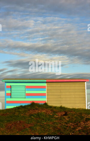 Deux cabines colorées dans la lumière du soir à saint helens duver nationaltrust site sur l'île de Wight, avec d'intéressants nuages au-dessus et des dunes. Banque D'Images