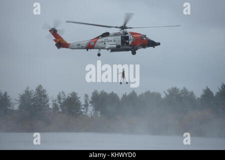 Maître de 2e classe Jordan Gilbert, un des techniciens de l'aviation au secteur de la Garde côtière canadienne, du fleuve Columbia est abaissé d'un hélicoptère Jayhawk MH-60 pendant une démonstration de recherche et de sauvetage à la gestion des catastrophes aux États-Unis/Chine Échange s'est déroulée au Camp Rilea situé dans la région de Warrenton, Ore., 16 novembre 2017. Des soldats de l'armée des États-Unis, du Pacifique de la Garde nationale de l'Oregon et de la République populaire de Chine, Sud de l'Armée populaire de libération du commandement de théâtre ont pris part à la 13ème itération de l'échange, qui a pour but de partager les leçons retenues au sujet de l'assistance humanitaire et les secours en cas de catastrophe Banque D'Images