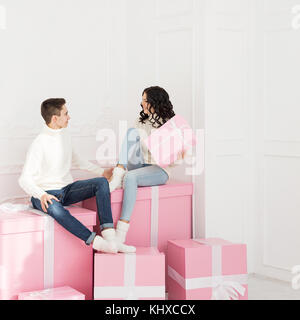 Un couple d'amoureux d'adolescents sont assis sur présente. Elle est titulaire d'un fort dans ses mains et regarde dans ses yeux. jours fériés. bonne année. joyeux noël. Banque D'Images