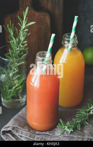 Detox jus d'agrumes en bouteille avec paille sur fond sombre. Fresh orange et jus de pamplemousse. Selective focus, tonique libre Banque D'Images