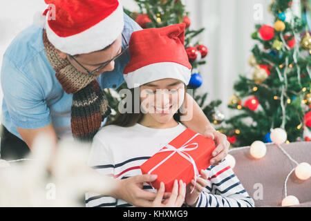 Asie amoureux couple, petit ami surprise copine en donnant cadeau de Noël au canapé avec Noël décoration arbre à la maison fête, vacances célébration mers Banque D'Images