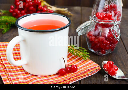 Sex berry thé dans un mug blanc sur un fond de bois foncé. Plateau avec viburnum. des petits fruits avec le sucre dans un bocal en verre verre thérapeutique.. Banque D'Images