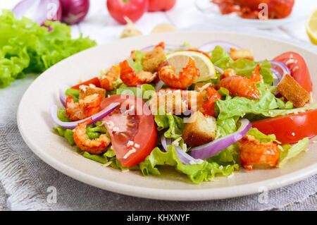 Savoureux de salade légère avec de la viande d'un cancer, crevettes, laitue, croûtons à l'ail, tomates, oignons rouges sur fond blanc. Banque D'Images