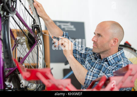 Handyman fixing bike roue dans son garage Banque D'Images