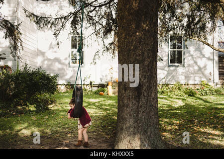 Fille sur balançoire pneu hanging from tree Banque D'Images