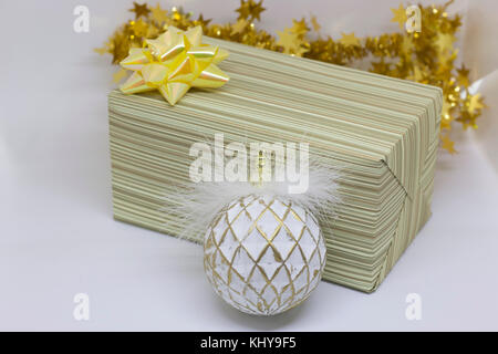 Boîte-cadeau avec un arc d'or et boule blanche sur un fond clair Banque D'Images