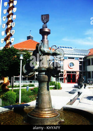 Cette illustration représente la fontaine Dettingen Iller située devant la mairie de Dettingen/Iller, en Allemagne. Il met en valeur la fontaine publique historique et son architecture environnante. L’image capture un point de repère important dans le contexte civique et historique de la région. Banque D'Images