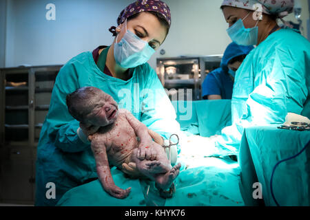 Médecin de salle d'opération de lale kilich montrant au nouveau-né à l'appareil photo Banque D'Images