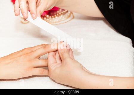 L'esthéticienne polish les ongles de la cliente avant de mettre du vernis à ongles Banque D'Images