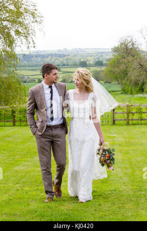 Newlywed couple strolling ensemble dans des jardins Banque D'Images