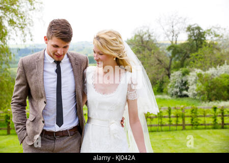 Newlywed couple strolling ensemble dans des jardins Banque D'Images
