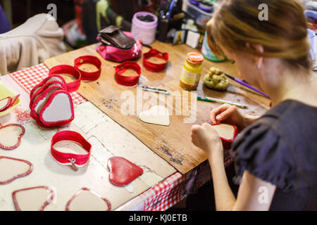 Brown-haired woman rouge en forme de cœur de la fabrication de sacs à main sur la table. Banque D'Images