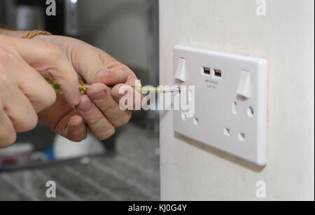 Richard Burr en installant une fiche USB dans un mur pour sa colonne de bricolage. Banque D'Images