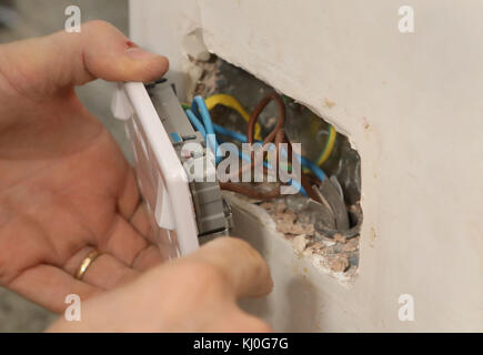 Richard Burr en installant une fiche USB dans un mur pour sa colonne de bricolage. Banque D'Images