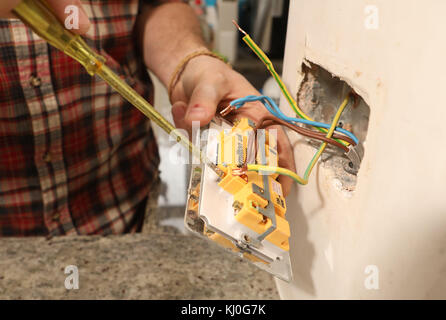 Richard Burr retirant une ancienne prise avant de brancher une fiche USB dans un mur pour sa colonne de bricolage. Banque D'Images