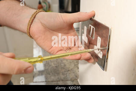 Richard Burr retirant une ancienne prise avant de brancher une fiche USB dans un mur pour sa colonne de bricolage. Banque D'Images