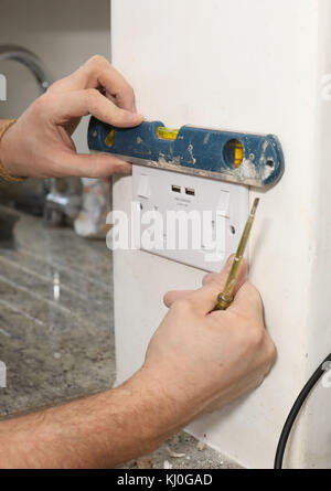 Richard Burr en installant une fiche USB dans un mur pour sa colonne de bricolage. Banque D'Images