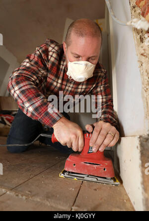 Richard Burr sablant un plancher en bois pour sa colonne de bricolage. Banque D'Images