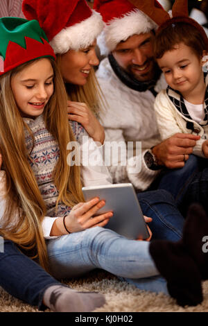 Les enfants avec les parents à la recherche de photos de Noël sur tablette Banque D'Images