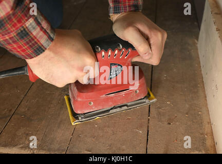 Richard Burr sablant un plancher en bois pour sa colonne de bricolage. Banque D'Images