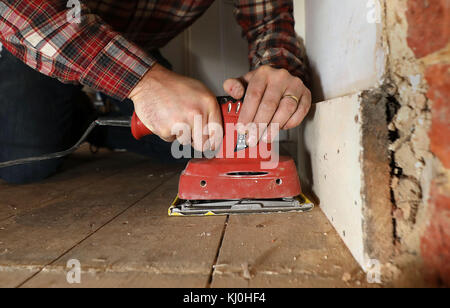 Richard Burr sablant un plancher en bois pour sa colonne de bricolage. Banque D'Images