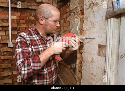 Richard Burr fore dans un mur pour sa colonne de bricolage. Banque D'Images